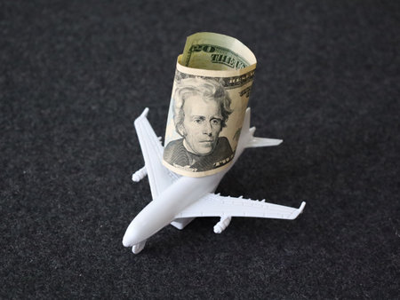 rolled up american twenty dollars banknote and figure of a white planeの写真素材