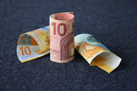 rolled swiss banknotes of ten francs and european ten euro bill