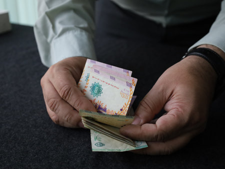 hands of a man holding and counting argentine peso billsの写真素材