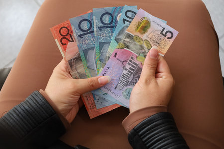 hands of a woman holding Australian dollars banknotes