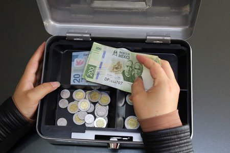 hands of a woman holding mexican money to keep it in a box