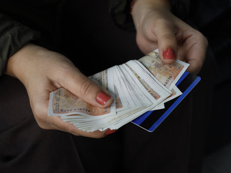 hand of a woman holding a credit card and pound sterling notes