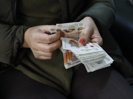 hands of a woman holding and counting sterling banknotesの写真素材