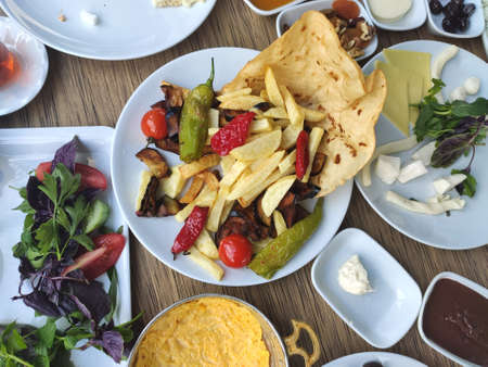 Breakfast table full of vegetables and cheese varieties, fried foods
