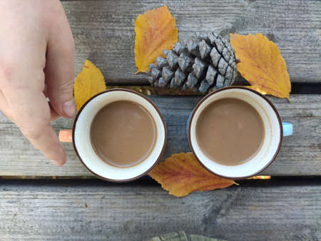 two cups of coffee, colorful leaves and woman's handの写真素材