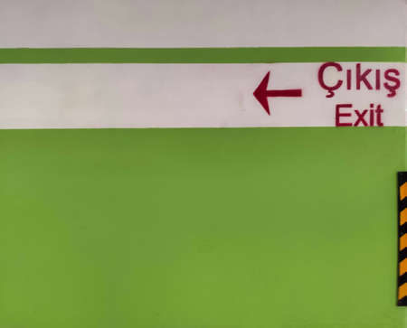 a green and white painted wall and an arrow pointing to the exit