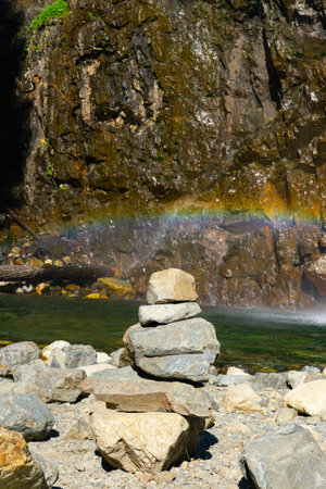 Cairn with water and rainbow in backgroundの写真素材