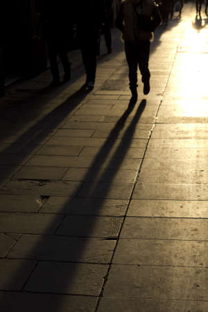 shadows of people walking down the street