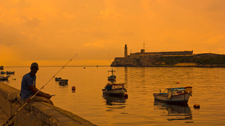 HAVANA, AUG 20: A Cuban fishing off the Malecon on Aug 8, 2011 in Havana. In the Bay of Havana, in the background the Morro Castle and the lighthouse. Cubaのeditorial素材
