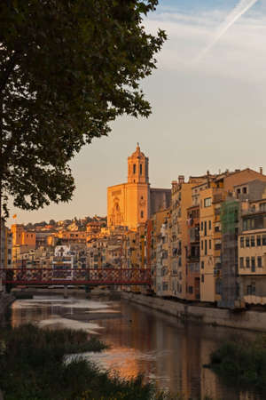Onyar river crossing the downtown of Girona with bell tower of Basilica of Sant Feliu in background....