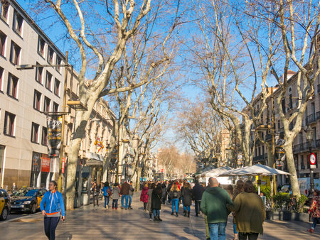 BARCELONA, SPAIN - FEBRUARY 15, 2018: The famous Ramblas street with walking tourists. Thousands of people walk daily by this popular pedestrian area 1.2 kilometer-longのeditorial素材