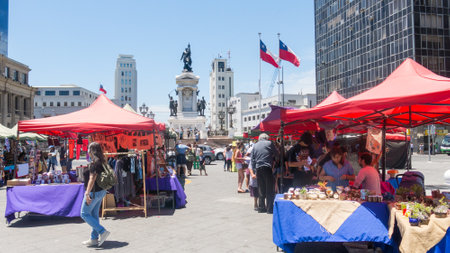 VALPARAISO, CHILE - JANUARY 2, 2018: Street market with people walking, in Sotomayor square, on the seafront of Valparaiso, in Chile. In the background, monument to the hero Arturo Prat.のeditorial素材