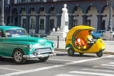HAVANA, CUBA - JANUARY 16, 2017: Old car and Cocotaxi in Old Havana. Coco taxi is an auto rickshaw type taxi vehicle in Cuba and a cheap way to go from one point to the other in Havana.のeditorial素材
