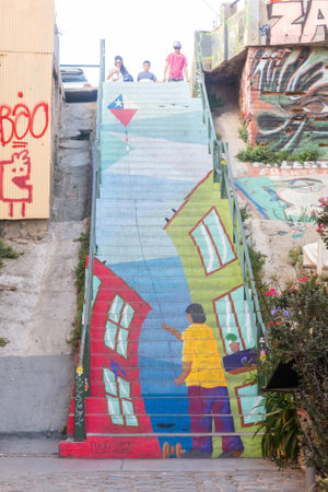 VALPARAISO, CHILE - JANUARY 2, 2018: stairway covered under colorful graffiti, with a person holding a kite with the flag of Chile, in Valparaiso, Chile.のeditorial素材