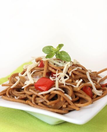 Fried noodles with vegetables and basil and cheese over green tableclothの写真素材