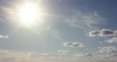 Blue sky with sun and cloudsの写真素材