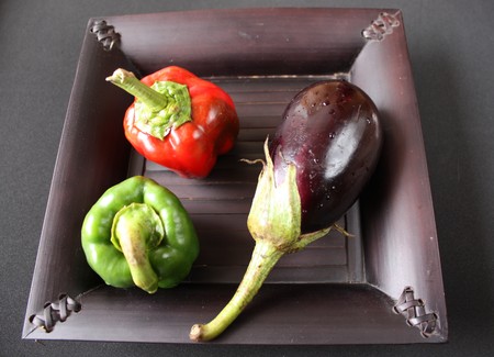 Fresh baby vegetables over black plateの写真素材