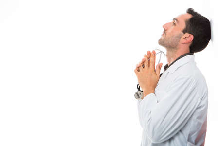 Half length profile portrait of a thoughtful male doctor holding stethoscopeの写真素材