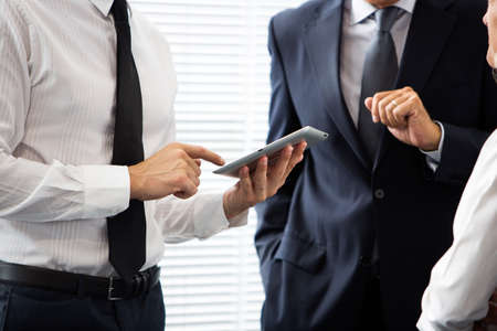 Half lenght portrait of two businessmen talking and using a digital tabletの写真素材