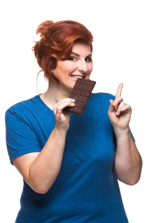 curvy woman eating chocolate tablet on the white backgroundの写真素材