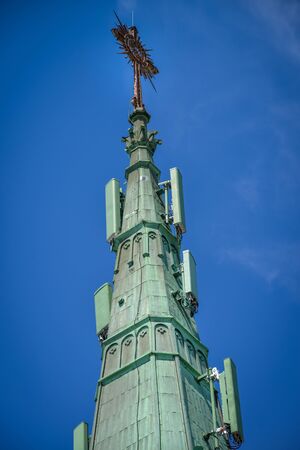 5g cell phone antennas on the oxidized copper gable of a cathedralの写真素材