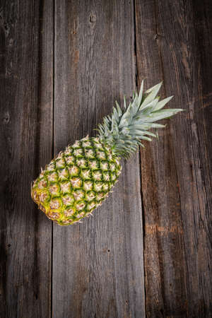 Big tropical pineapple with its leaves on a barn wood boardの写真素材
