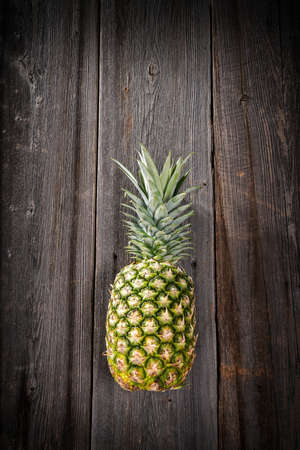 Big tropical pineapple with its leaves on a barn wood board