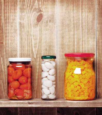 Preserved  autumn vegetables on shelf near a brown wooden wallの写真素材