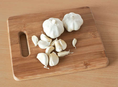 Garlic on brown cutting bamboo board used for cooking 