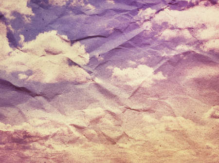 Vintage clouds and sky on crumpled paper texture.