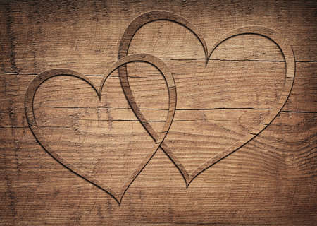 Two wooden hearts placed on a brown wood board.の写真素材