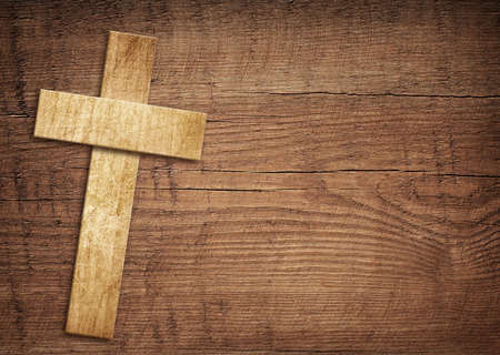 Wooden cross on brown old tabletop or wall surface.の写真素材
