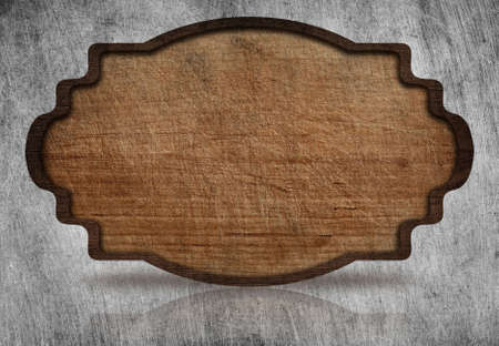 Brown wooden ornate, scratched signboard with dark frame and reflection on grunge metal background.の写真素材