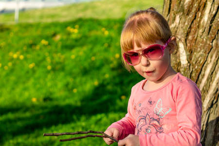 Portrait of a funny child in glasses playing in a summer park. Happy childhoodの写真素材