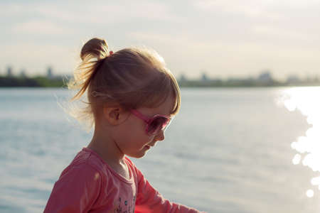 The child runs on the coast in the sand, in clothes.の写真素材