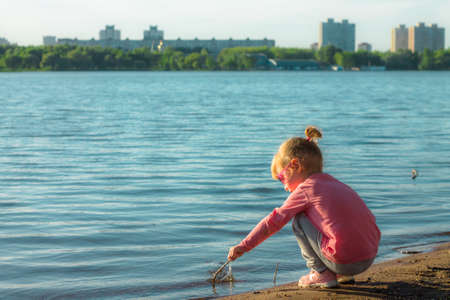 The child runs on the coast in the sand, in clothes.の写真素材