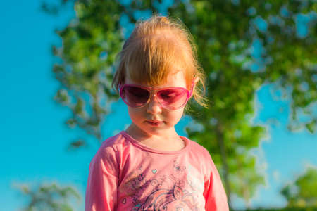 Portrait of a funny child in glasses playing in a summer park. Happy childhoodの写真素材