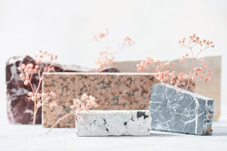 Composition of travertine and granite blocks and gypsophila grass. Abstract modern background. Natural materials.
