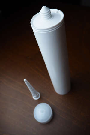 Part of sealant cartridge. Sealant cartridge on the table. White caulk on wood table. Sealant for fix water leak.の写真素材