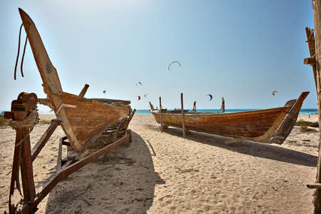 Boats on the beach at sunrise time Dubai, kite surfers in the background