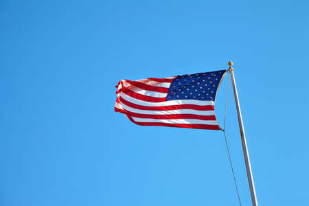 American flag waving in blue sky in the wind