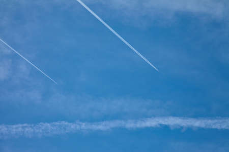 Airplanes flying in the blue sky among clouds and sunlightの写真素材