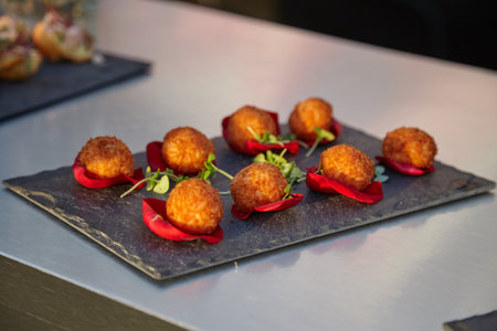 Golden crispy fried snacks served on a slate plate with charming rose petals as garnish
