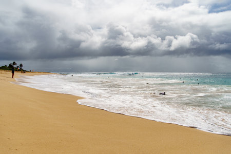 A beach on a cloudy day with waves crashing on the shoreの写真素材