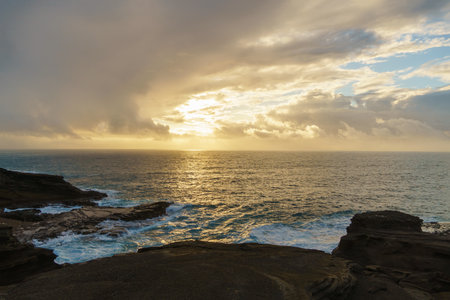 Beautiful sunset over water with rocks in foregroundの写真素材