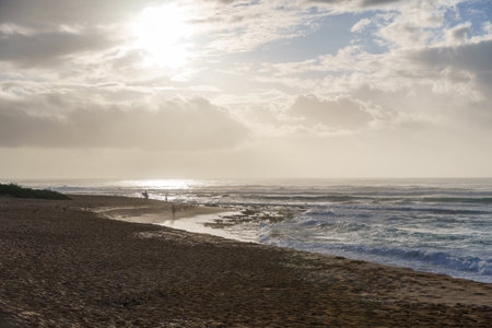 A beach with cloudy sky, sun shining through clouds, water, sky, beach..の写真素材