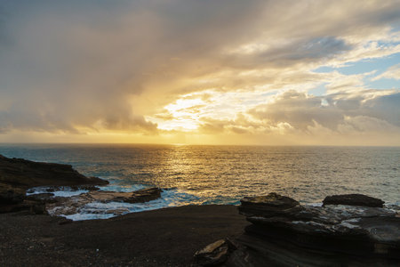 Beautiful sunset reflecting on calm water with rocks in foregroundの写真素材