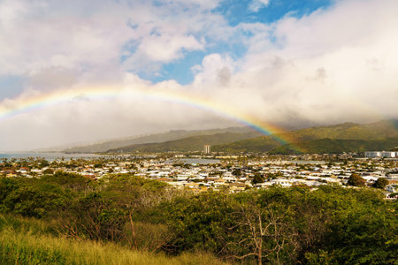 Rainbow arches across sky above distant city, blending with landscapeの写真素材