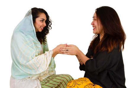 2 Malaysian ladies in traditional dress shaking handsの写真素材
