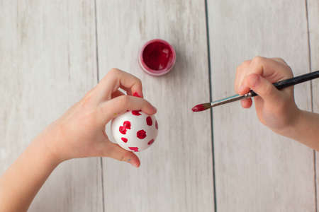 Easter preparation. Little girl paints eggs. Two dozen white eggs on wooden background. Inspiration. Time with kids.の写真素材